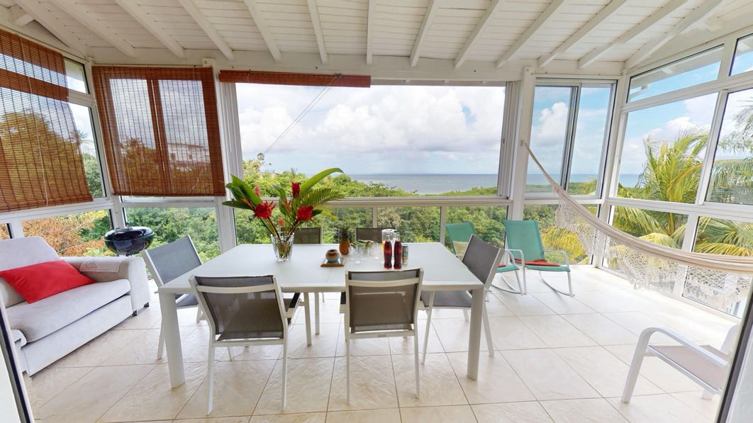 Véranda de la Villa Nature avec table à manger, hamac et vue sur la mer au Gosier.